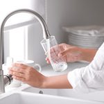 Woman,Pouring,Water,Into,Glass,In,Kitchen,,Closeup