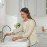 Woman,Filling,Glass,With,Water,From,Tap,In,Kitchen