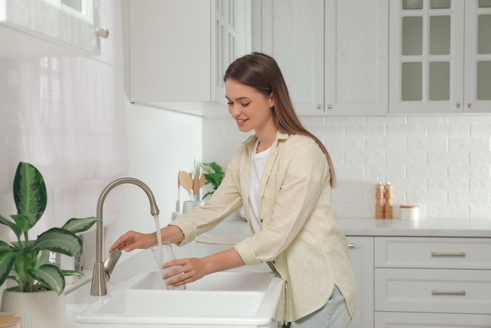 Woman,Filling,Glass,With,Water,From,Tap,In,Kitchen